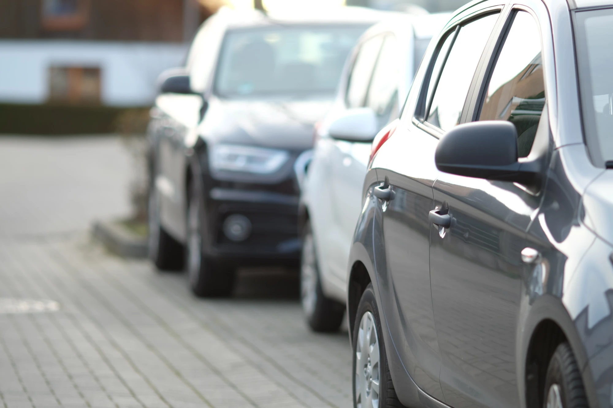 Cars parked in a row on the brick lot outside the hotel