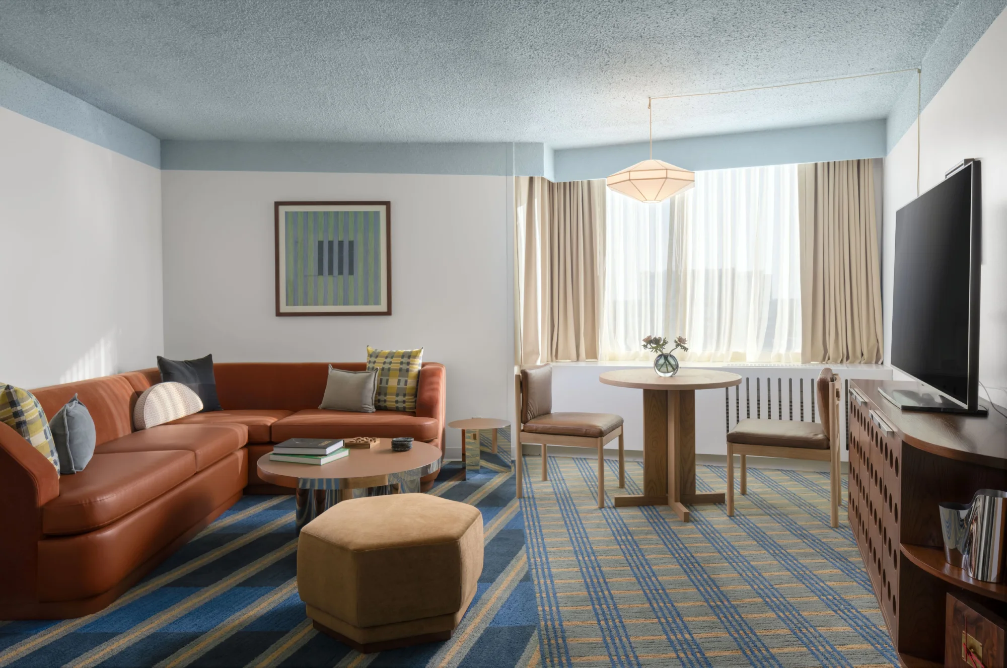 Suite living room with a leather sectional, dining table for two and floor-to-ceiling windows